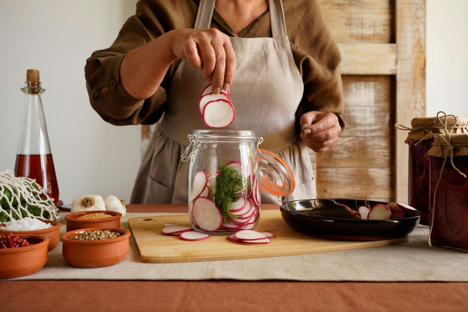 person putting radishes into a mason jar